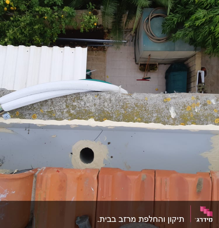 גג עם רעפים אדומים וצינור לבן מחובר